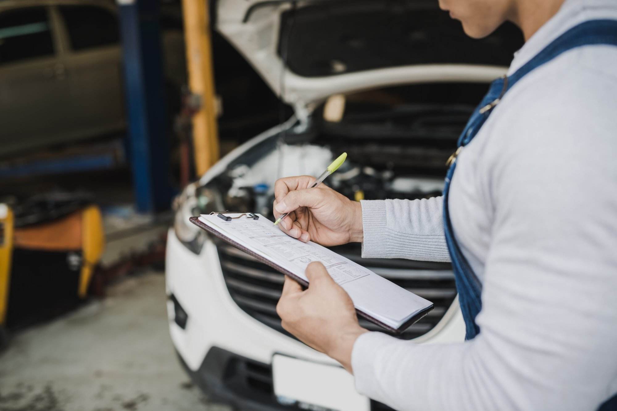 Hand young man mechanic holding clipboard checklist car service center repair scaled